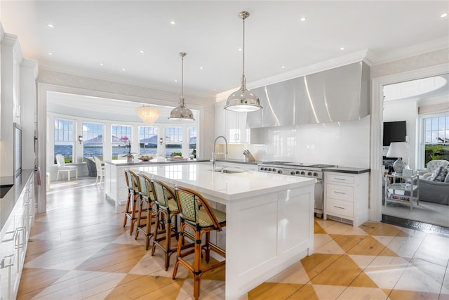 59 Shore Rd, Westhampton, NY 11977 - kitchen with high end stainless steel range, white cabinetry, a large island with sink, a breakfast bar, and backsplash