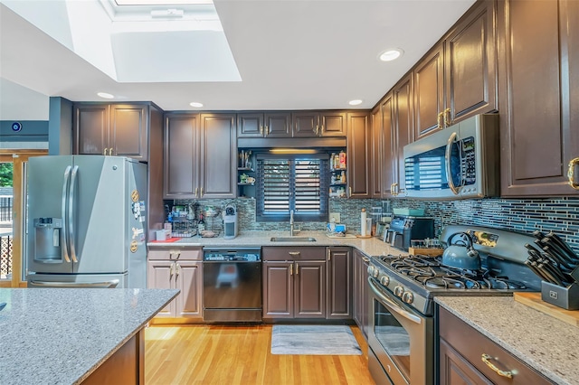41 W 21st St, Deer Park, NY 11729 - kitchen featuring appliances with stainless steel finishes, light wood-style floors, light stone countertops, a skylight, and backsplash