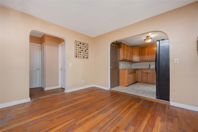 75-06A 255th St Unit A, Glen Oaks, NY 11004 - kitchen featuring arched walkways, freestanding refrigerator, light wood-type flooring, and tasteful backsplash