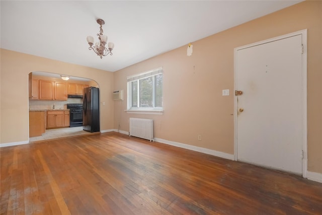75-06A 255th St Unit A, Glen Oaks, NY 11004 - unfurnished living room featuring radiator heating unit, light wood-style flooring, arched walkways, a chandelier, and a wall mounted air conditioner