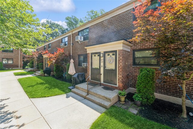 217-22 73rd Ave Upper, Upper, Oakland Gardens, NY 11364 - doorway to property with brick siding, cooling unit, and a lawn