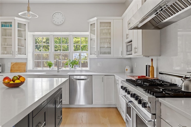 12 N Rd, Laurel Hollow, NY 11771 - kitchen featuring stainless steel appliances, ventilation hood, light countertops, white cabinets, and decorative light fixtures