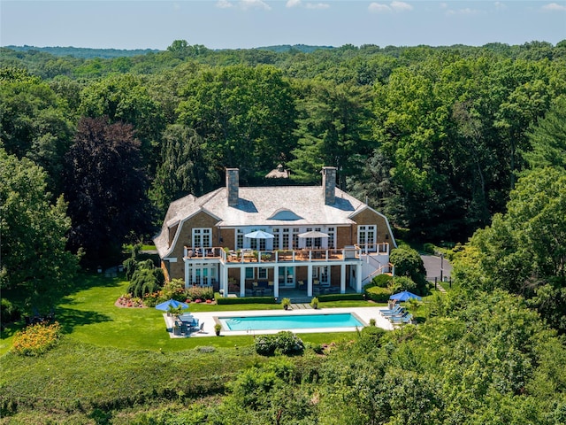 12 N Rd, Laurel Hollow, NY 11771 - back of house featuring a wooded view, an outdoor pool, a chimney, a yard, and a deck