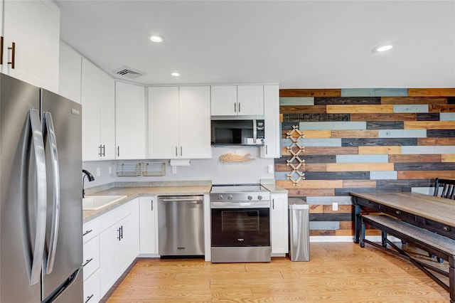 1 Anchorage Way Unit 301, Freeport, NY 11520 - kitchen with appliances with stainless steel finishes, light countertops, white cabinets, light wood-style flooring, and recessed lighting