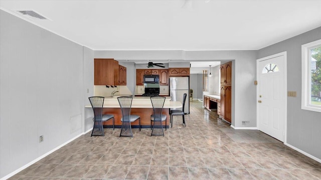 107 Croydon Rd, Yonkers, NY 10710 - kitchen featuring black microwave, freestanding refrigerator, a peninsula, brown cabinets, and ceiling fan