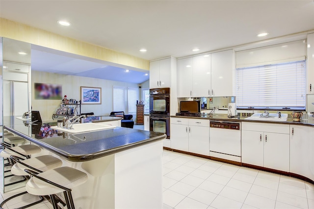 7015 170th St, Fresh Meadows, NY 11365 - kitchen with white dishwasher, dark countertops, a kitchen bar, white cabinets, and recessed lighting