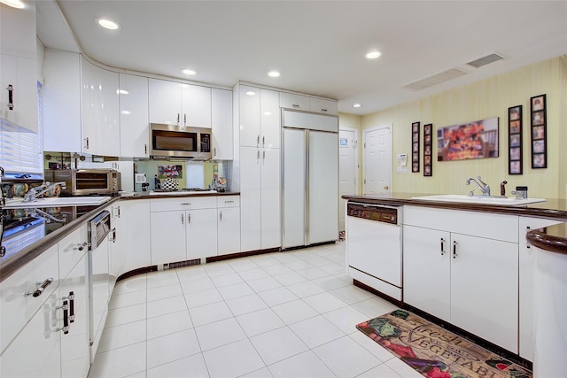 7015 170th St, Fresh Meadows, NY 11365 - kitchen with white dishwasher, paneled fridge, dark countertops, stainless steel microwave, and white cabinetry