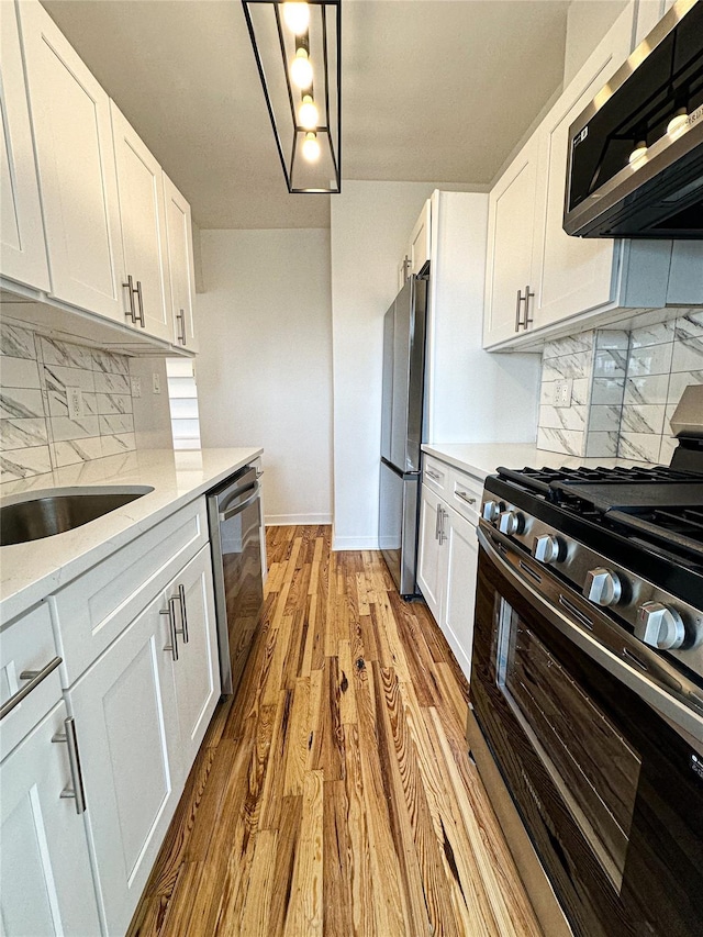 35-24 78th St Unit A67, Jackson Heights, NY 11372 - kitchen with appliances with stainless steel finishes, white cabinetry, decorative backsplash, light wood-type flooring, and light stone counters