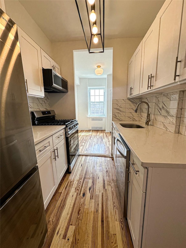 35-24 78th St Unit A67, Jackson Heights, NY 11372 - kitchen with stainless steel appliances, radiator, light wood-style floors, and white cabinets
