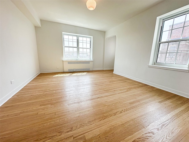 35-24 78th St Unit A67, Jackson Heights, NY 11372 - unfurnished room with radiator heating unit, plenty of natural light, light wood finished floors, and arched walkways