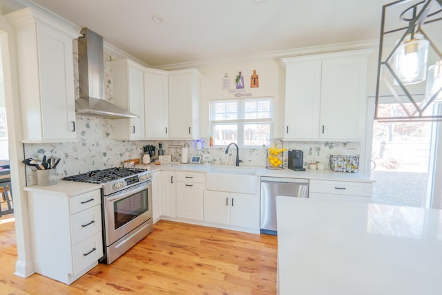 37 William St, Bohemia, NY 11716 - kitchen with appliances with stainless steel finishes, wall chimney range hood, backsplash, light wood-style flooring, and light countertops