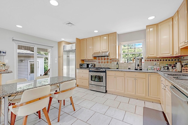 97 Burnham Ave, Roslyn Heights, NY 11577 - kitchen with appliances with stainless steel finishes, under cabinet range hood, backsplash, light tile patterned floors, and recessed lighting