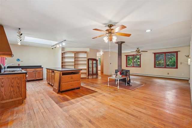 27 Jagger Ln, Westhampton, NY 11977 - kitchen featuring dark countertops, brown cabinetry, a skylight, and a baseboard radiator