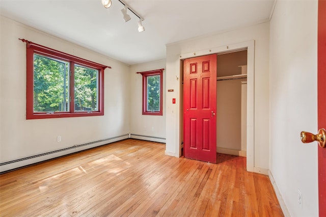 27 Jagger Ln, Westhampton, NY 11977 - unfurnished bedroom with light wood-type flooring, a baseboard heating unit, rail lighting, crown molding, and a closet