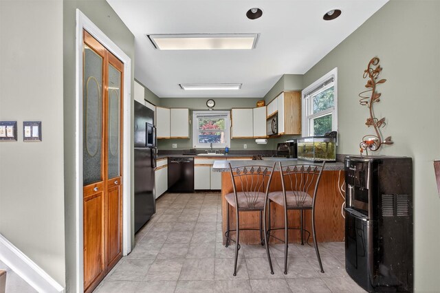 3324 Sycamore Ln, Yorktown Heights, NY 10598 - kitchen with black appliances, a peninsula, dark countertops, a breakfast bar, and white cabinets