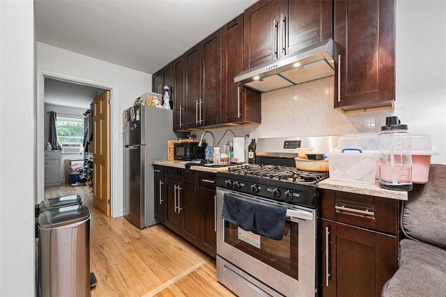 74-25 93rd Ave, Woodhaven, NY 11421 - kitchen with stainless steel appliances, under cabinet range hood, light wood-type flooring, dark brown cabinetry, and decorative backsplash