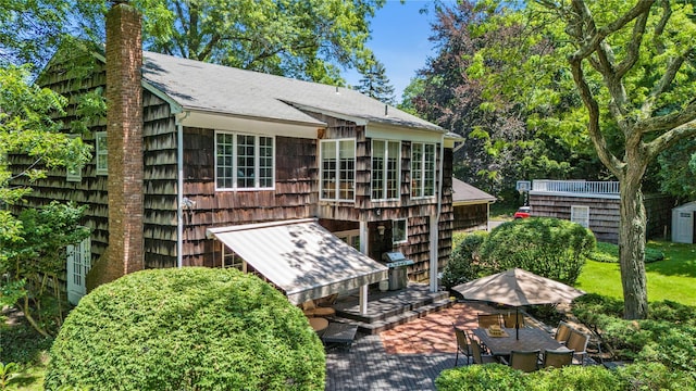 26 Rolling Dr, Brookville, NY 11545 - back of house with a storage shed, roof with shingles, and a chimney