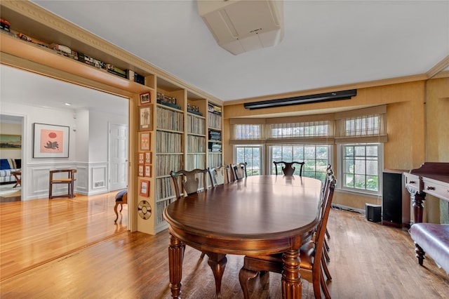26 Rolling Dr, Brookville, NY 11545 - dining space featuring wood finished floors, a decorative wall, crown molding, and wainscoting