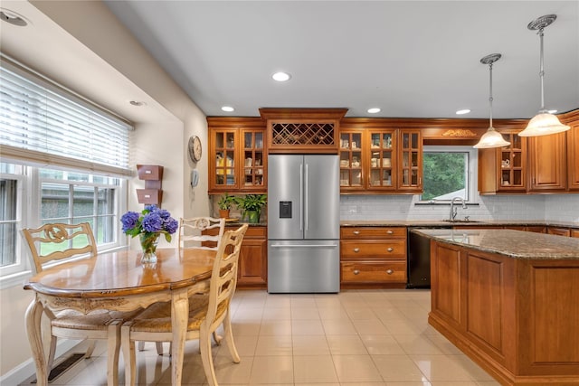 26 Rolling Dr, Brookville, NY 11545 - kitchen with stainless steel fridge, brown cabinetry, tasteful backsplash, recessed lighting, and dark stone countertops