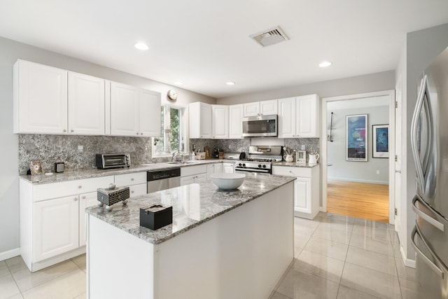 70 Hickory St, Blauvelt, NY 10913 - kitchen featuring appliances with stainless steel finishes, tasteful backsplash, light tile patterned floors, a center island, and white cabinets