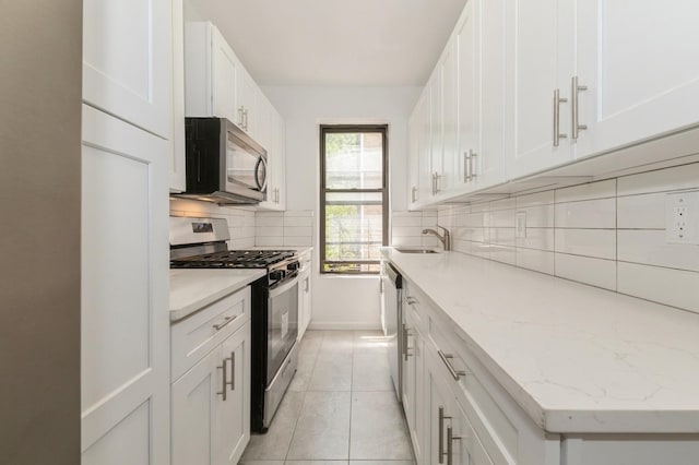 1110 Caton Ave Unit 5C, Brooklyn, NY 11218 - kitchen featuring stainless steel appliances, decorative backsplash, white cabinetry, light stone counters, and light tile patterned floors