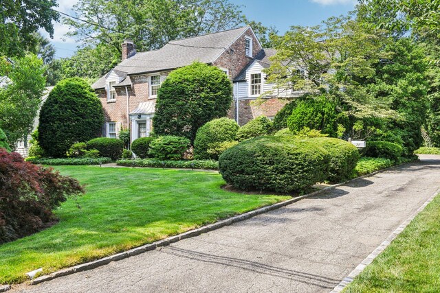 21 Orchard Dr, East Williston, NY 11596 - view of front of home with brick siding, a chimney, and a front yard
