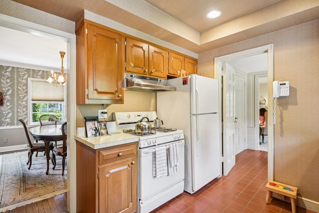 21 Orchard Dr, East Williston, NY 11596 - kitchen featuring under cabinet range hood, gas range gas stove, wallpapered walls, a chandelier, and light countertops