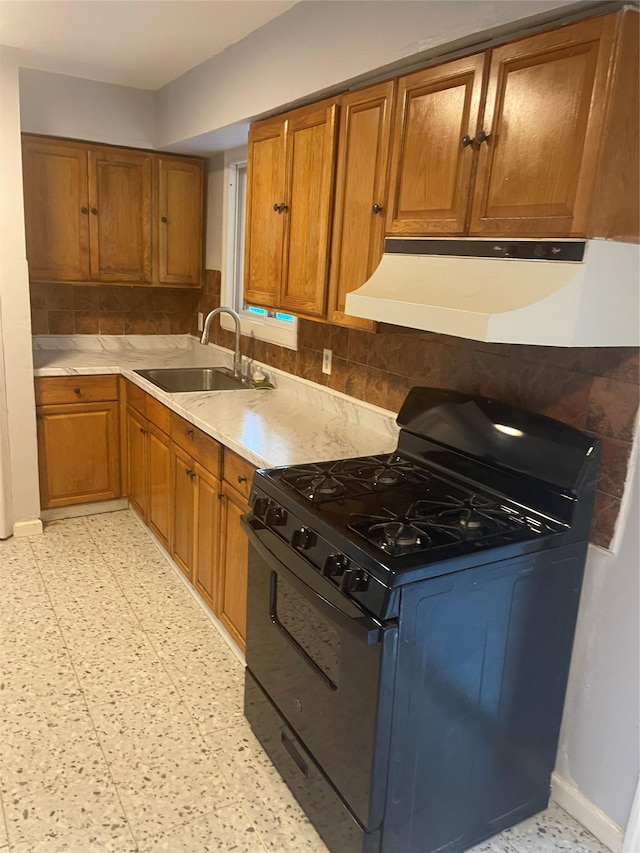 38 Sheffield Dr, Middletown, NY 10940 - kitchen with black gas range oven, under cabinet range hood, brown cabinetry, and tasteful backsplash