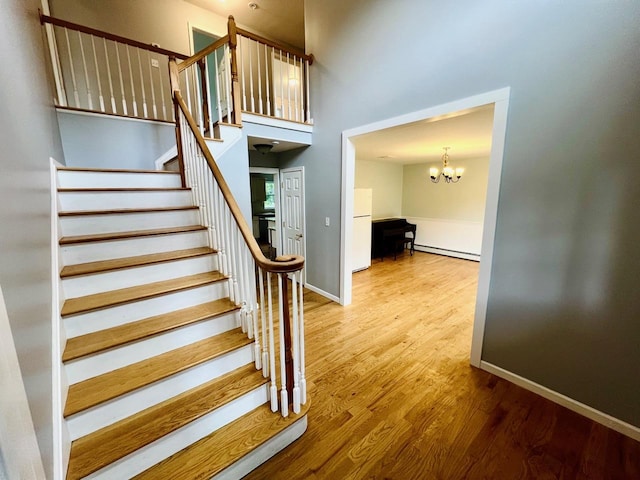 232 Minisink Tpke, Westtown, NY 10998 - stairway featuring a baseboard radiator, wood finished floors, a chandelier, and a towering ceiling