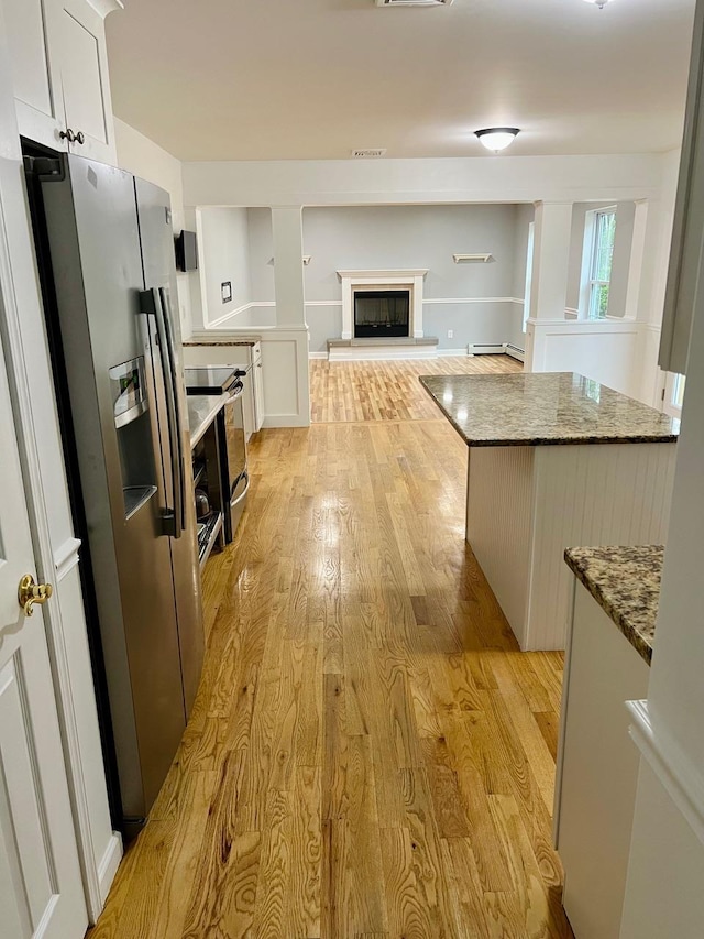 232 Minisink Tpke, Westtown, NY 10998 - kitchen with stainless steel fridge, stove, light wood-style floors, a glass covered fireplace, and white cabinetry