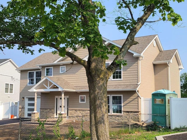 56 Bayberry Ln, Levittown, NY 11756 - view of front of home featuring stone siding, roof with shingles, and a fenced front yard