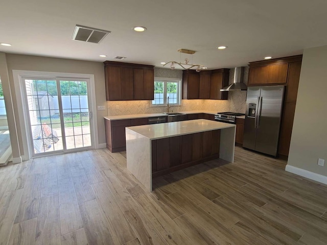 56 Bayberry Ln, Levittown, NY 11756 - kitchen featuring stainless steel appliances, wall chimney range hood, light wood-type flooring, light countertops, and decorative backsplash