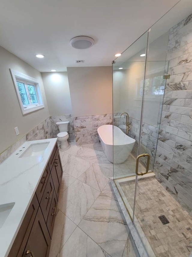 56 Bayberry Ln, Levittown, NY 11756 - bathroom with tile walls, marble finish floors, a soaking tub, a stall shower, and wainscoting