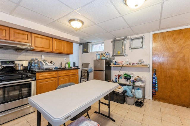114 Birchwood Park Dr, Syosset, NY 11791 - kitchen featuring stainless steel appliances, under cabinet range hood, a paneled ceiling, light tile patterned flooring, and brown cabinetry