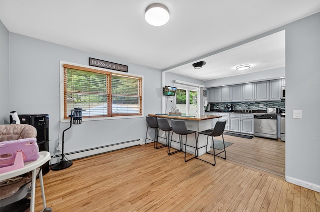 411 Fair Oaks Rd, Middletown, NY 10940 - kitchen with stainless steel dishwasher, a baseboard radiator, light wood-style flooring, a kitchen breakfast bar, and gray cabinetry