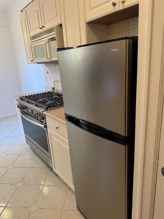 2925 Matthews Ave Unit 5F, Bronx, NY 10467 - kitchen featuring appliances with stainless steel finishes, decorative backsplash, light countertops, light tile patterned flooring, and white cabinetry