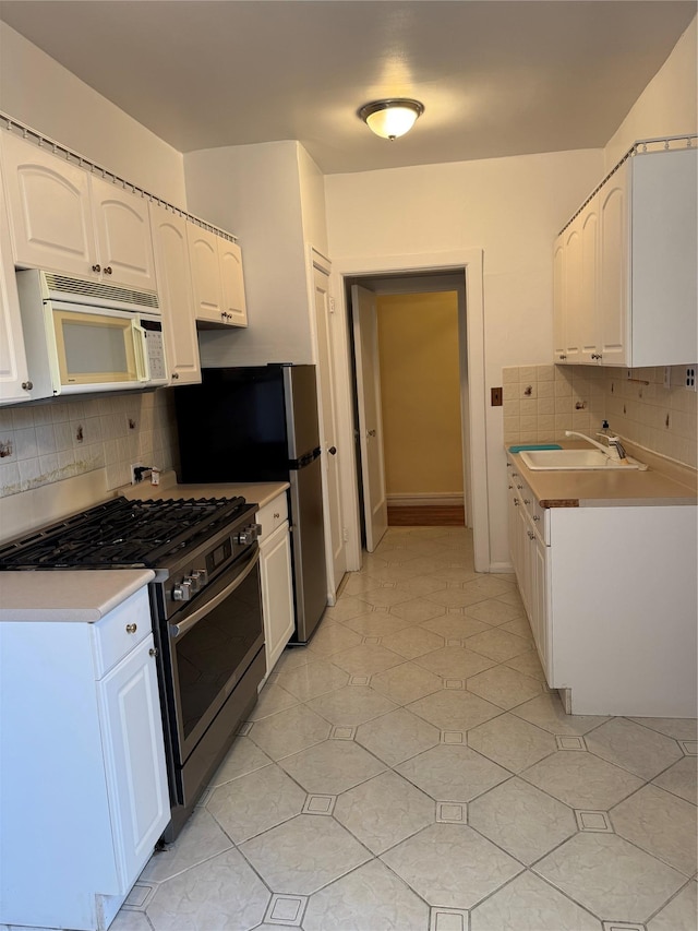 2925 Matthews Ave Unit 5F, Bronx, NY 10467 - kitchen featuring white microwave, stainless steel gas range, tasteful backsplash, and white cabinets