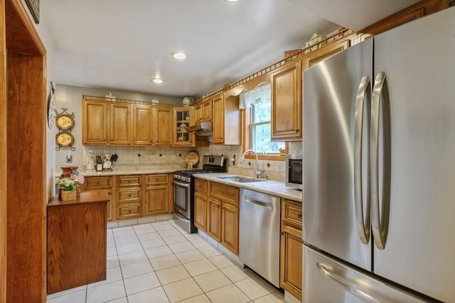 445 Wellington Rd, Mineola, NY 11501 - kitchen with stainless steel appliances, decorative backsplash, light tile patterned flooring, brown cabinetry, and under cabinet range hood