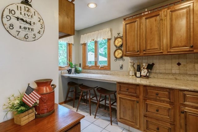 445 Wellington Rd, Mineola, NY 11501 - kitchen featuring brown cabinets, tasteful backsplash, light tile patterned floors, recessed lighting, and built in study area