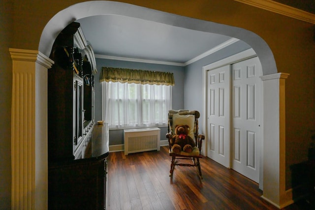 445 Wellington Rd, Mineola, NY 11501 - sitting room with radiator, arched walkways, dark wood finished floors, ornate columns, and ornamental molding