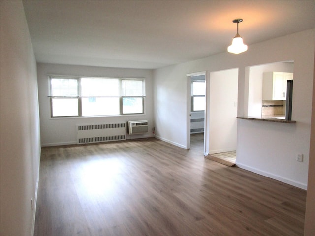 324 Post Ave Apt 8-J, Westbury, NY 11590 - unfurnished room with radiator heating unit, a wall unit AC, and wood finished floors