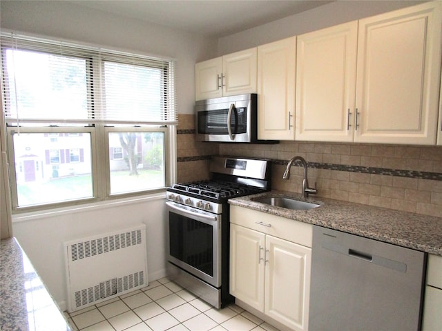 324 Post Ave Apt 8-J, Westbury, NY 11590 - kitchen featuring stainless steel appliances, radiator heating unit, decorative backsplash, white cabinetry, and light stone countertops