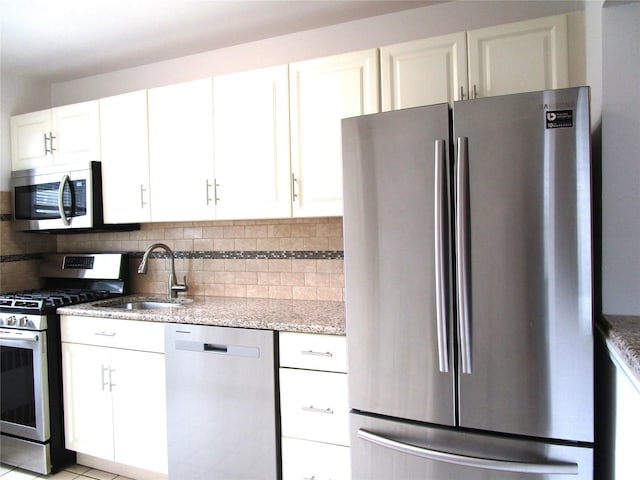 324 Post Ave Apt 8-J, Westbury, NY 11590 - kitchen with stainless steel appliances, white cabinets, light stone counters, and decorative backsplash