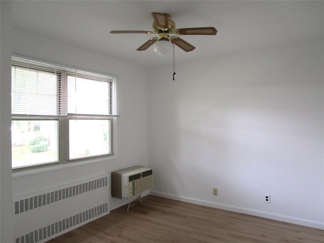 324 Post Ave Apt 8-J, Westbury, NY 11590 - unfurnished room featuring radiator heating unit, wood finished floors, ceiling fan, and a wall unit AC