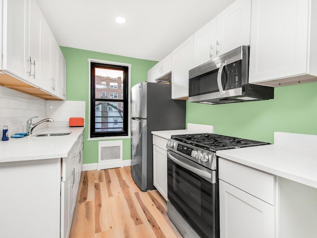 75 W 238th St Unit 3H, Bronx, NY 10463 - kitchen featuring appliances with stainless steel finishes, light wood-type flooring, light countertops, tasteful backsplash, and white cabinets