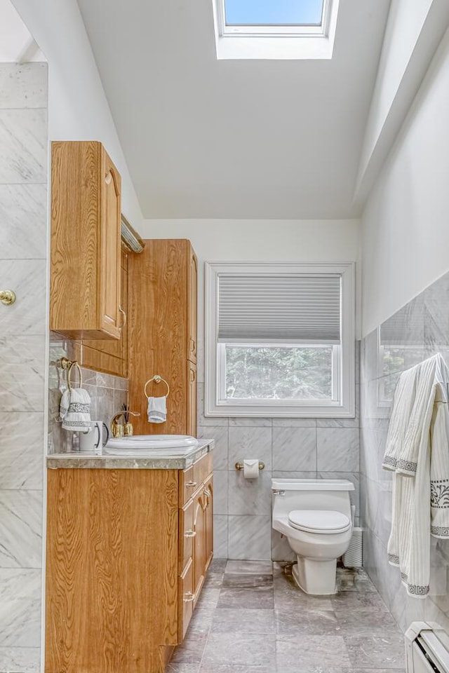 28 Lime Kiln Rd, Suffern, NY 10901 - bathroom featuring tile walls, baseboard heating, vanity, a skylight, and vaulted ceiling