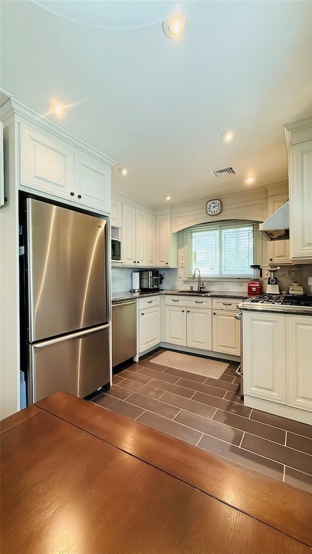 64 Meadowfarm Rd, Manhasset Hills, NY 11040 - kitchen featuring appliances with stainless steel finishes, backsplash, white cabinetry, exhaust hood, and dark wood-type flooring