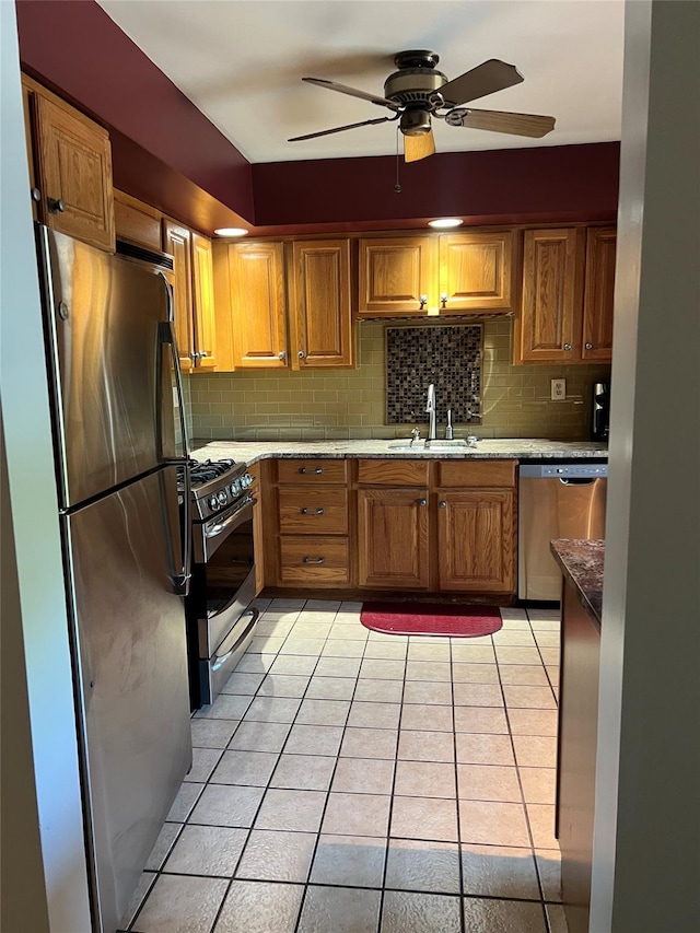 13 Butternut Ct, Highland Mills, NY 10930 - kitchen featuring appliances with stainless steel finishes, light tile patterned floors, brown cabinets, backsplash, and ceiling fan