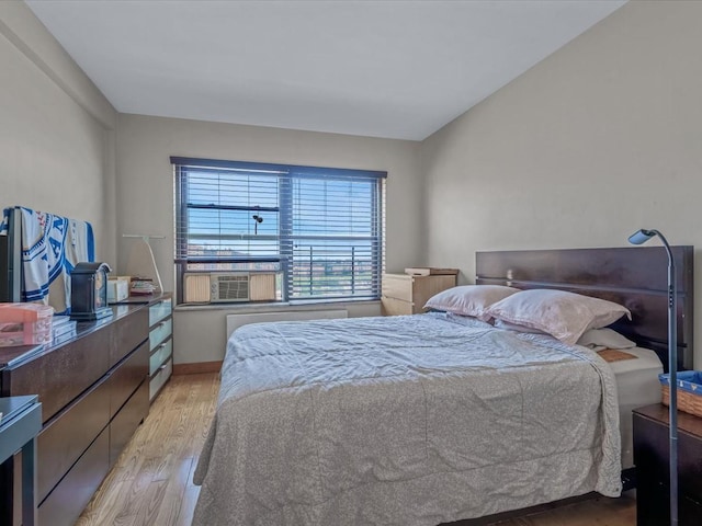 99-05 63rd Dr Unit 7R, Rego Park, NY 11374 - bedroom with light wood-style flooring, cooling unit, and radiator heating unit