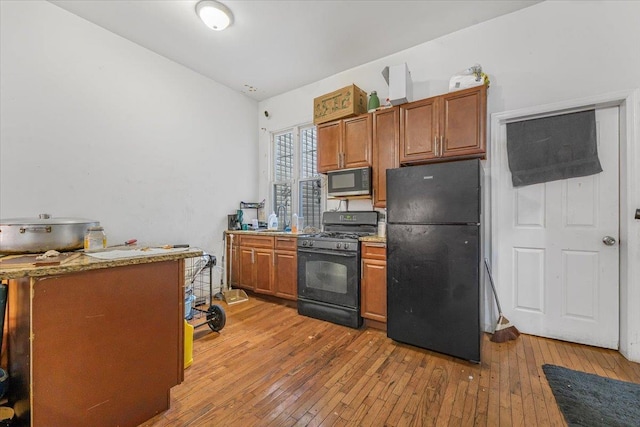 1047 Trinity Ave, Bronx, NY 10456 - kitchen featuring black appliances, brown cabinetry, light wood-style floors, and lofted ceiling